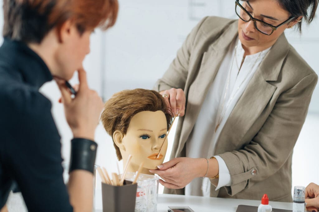 Showcasing hair styling technique to a student on a dummy