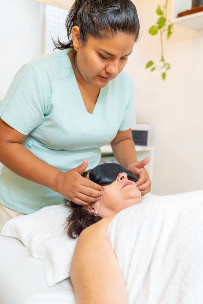 Skincare therapist performing facial massage on client
