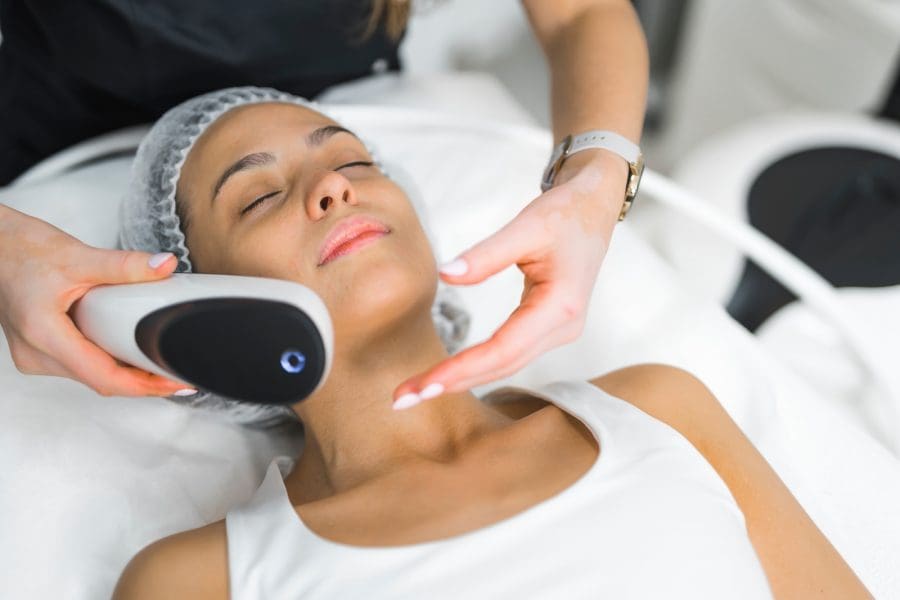 Fractional laser used in professional SPA facility. Spot treatment concept. Medium closeup indoor portrait of young Latin model in her mid 20s lying down when unrecognizable beautician does her treatment. High quality photo